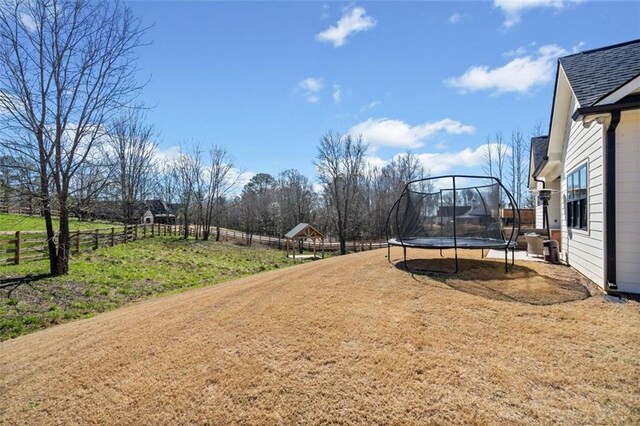 view of yard featuring a trampoline and fence