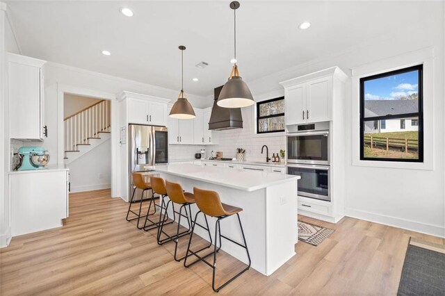 living area featuring ornate columns, visible vents, light wood finished floors, and a ceiling fan