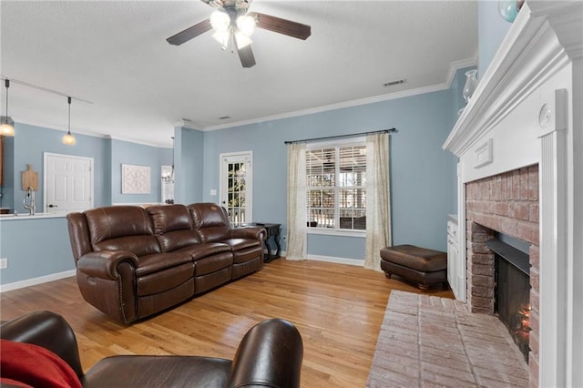 living room with a brick fireplace, ornamental molding, light hardwood / wood-style flooring, and ceiling fan