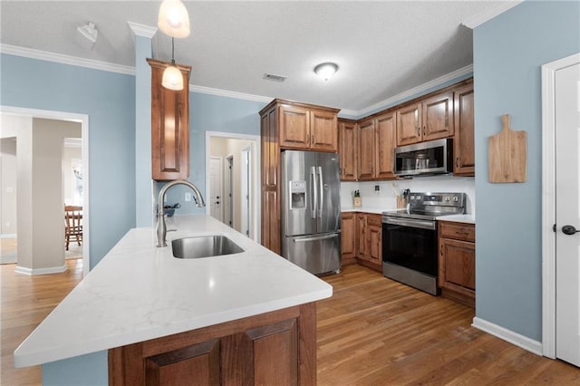 kitchen with sink, crown molding, stainless steel appliances, and pendant lighting