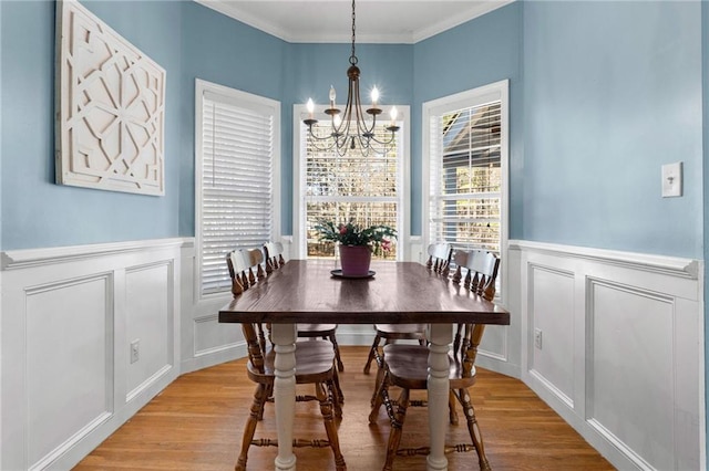 dining room with light hardwood / wood-style floors, ornamental molding, and an inviting chandelier