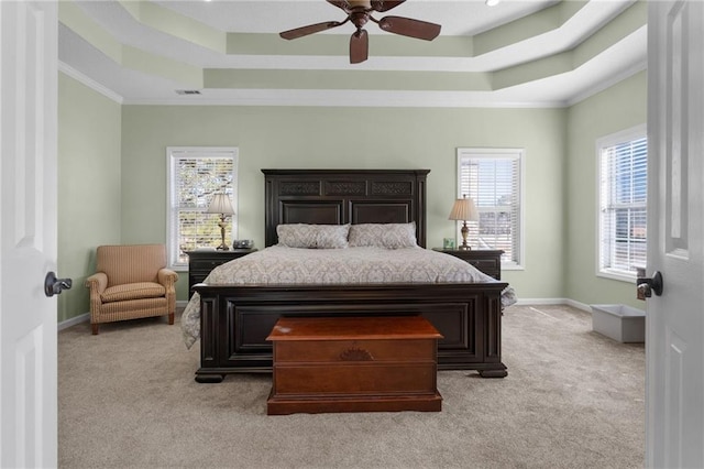 carpeted bedroom with ceiling fan, crown molding, and a tray ceiling