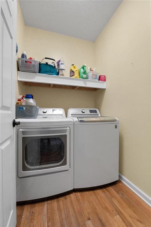 clothes washing area featuring light hardwood / wood-style floors and washing machine and clothes dryer