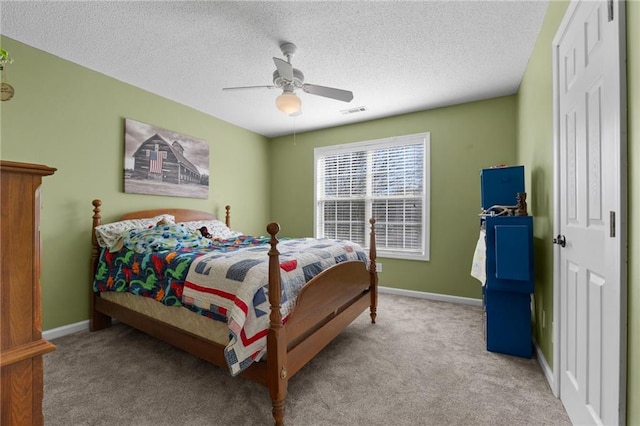 bedroom with ceiling fan, light colored carpet, and a textured ceiling