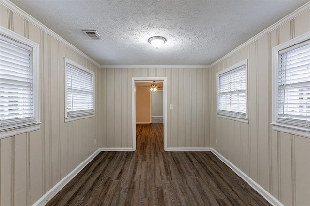 spare room with a textured ceiling, ornamental molding, and dark hardwood / wood-style floors