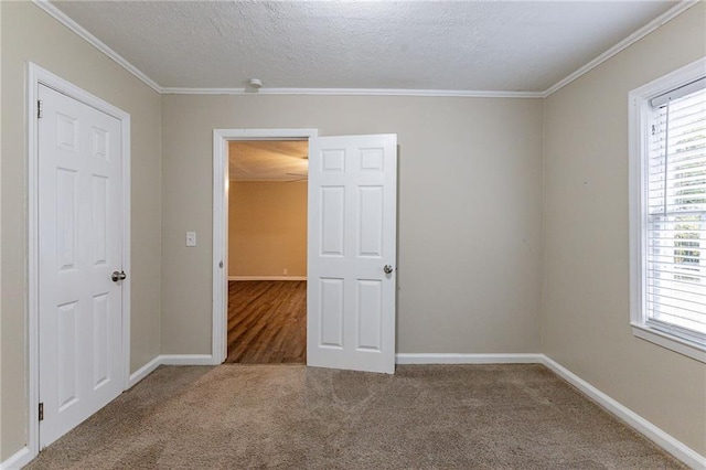 empty room with a textured ceiling, carpet floors, and crown molding