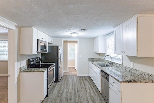 kitchen featuring stainless steel appliances, white cabinets, and a healthy amount of sunlight