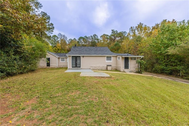 rear view of property featuring a patio, a lawn, and french doors