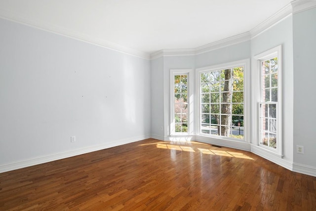 empty room with a wealth of natural light, hardwood / wood-style floors, and crown molding