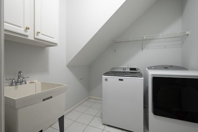 clothes washing area with light tile patterned floors, sink, separate washer and dryer, and cabinets