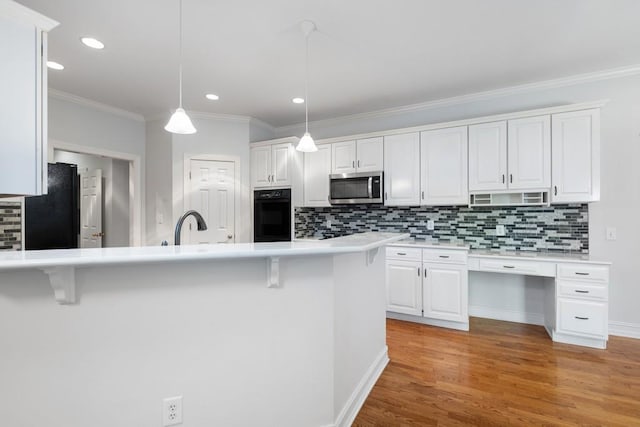 kitchen featuring light hardwood / wood-style flooring, white cabinets, black appliances, and a breakfast bar area