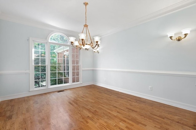 unfurnished room featuring a notable chandelier, hardwood / wood-style flooring, and crown molding