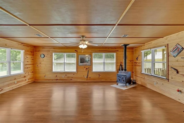 10 Shadow Ln, Cartersville, GA 30120 - unfurnished living room with wooden walls, wood finished floors, a wood stove, healthy amount of natural light, and ceiling fan