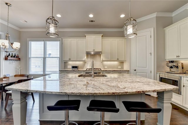 kitchen featuring dark wood-style flooring, visible vents, tasteful backsplash, stainless steel microwave, and white cabinetry