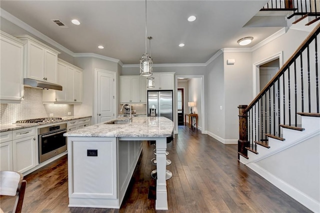 kitchen with dark wood-style flooring, under cabinet range hood, white cabinets, a sink, and stainless steel appliances