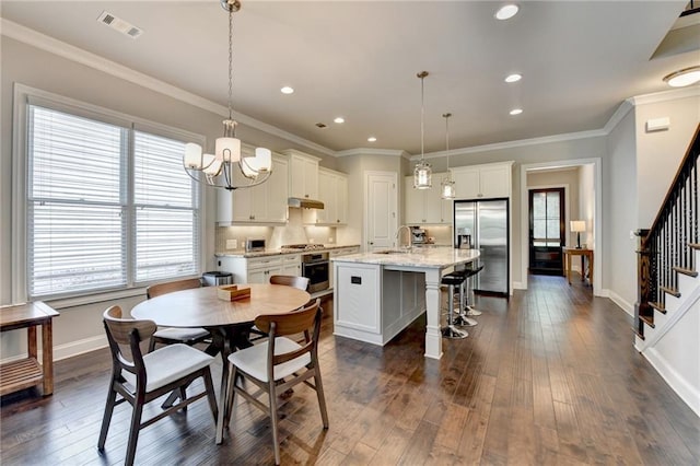 dining space with visible vents, plenty of natural light, dark wood finished floors, and stairway