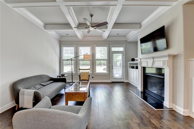 living area featuring dark wood-style flooring, a fireplace, a ceiling fan, baseboards, and beamed ceiling