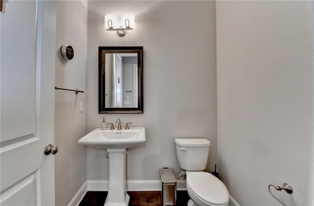 half bathroom with baseboards and toilet
