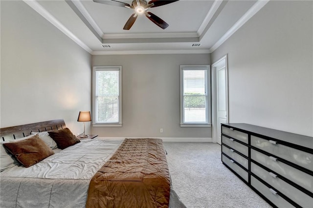 carpeted bedroom with crown molding, baseboards, multiple windows, and a raised ceiling