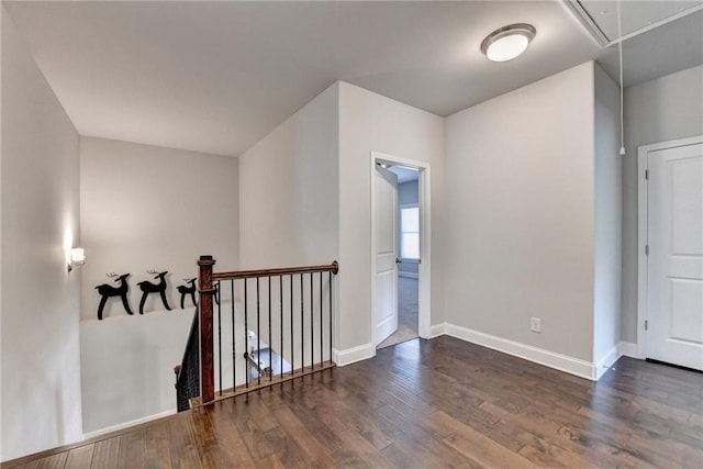 additional living space featuring baseboards, attic access, and dark wood-style flooring