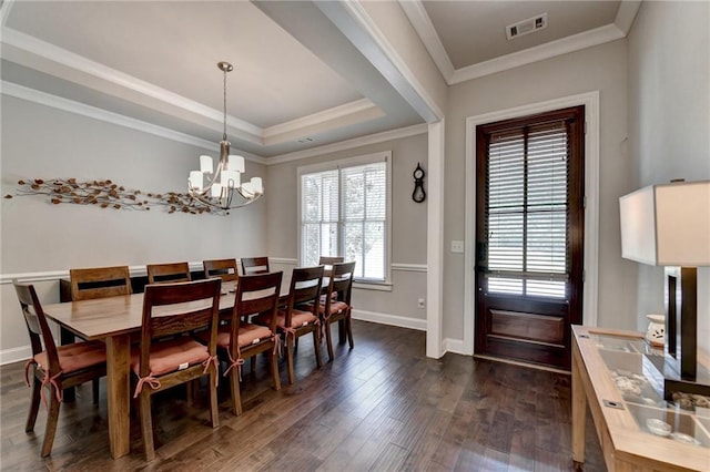 dining space with an inviting chandelier, dark wood finished floors, baseboards, a tray ceiling, and visible vents