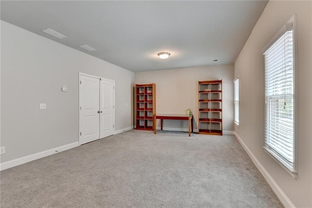 unfurnished room featuring baseboards, visible vents, and light carpet