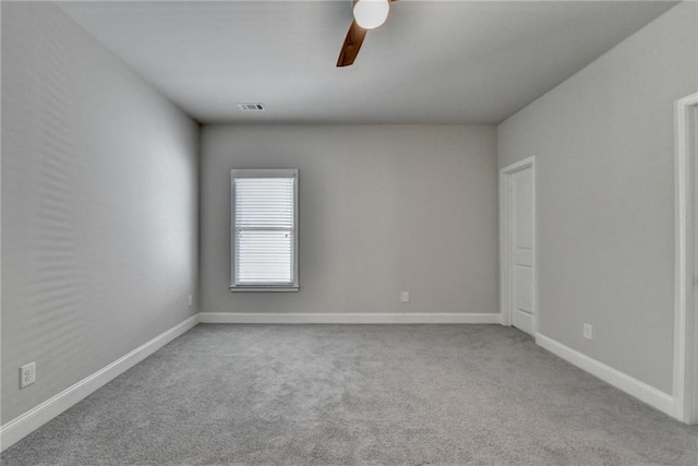 carpeted spare room featuring baseboards, ceiling fan, and visible vents
