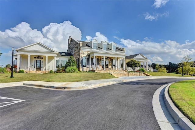 view of front of home with a porch, uncovered parking, and a front yard