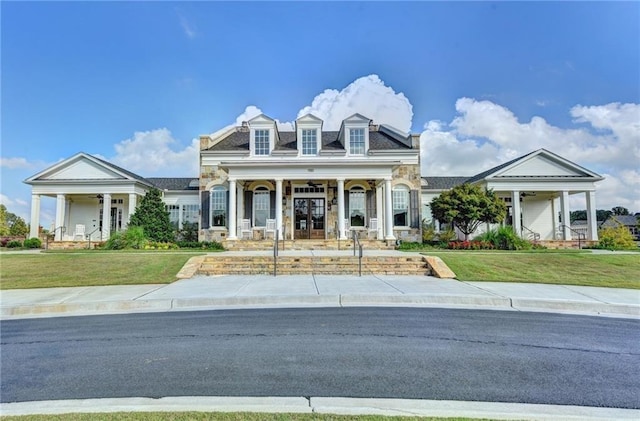view of front of house with covered porch, stone siding, ceiling fan, and a front yard