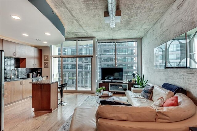 living room featuring sink, light wood-type flooring, and floor to ceiling windows