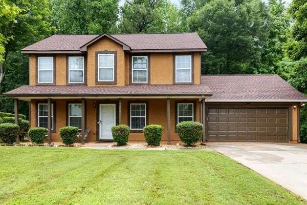 4424 English Loop, Stonecrest, GA 30038 - view of front facade with a garage, concrete driveway, covered porch, a front yard, and view of wooded area
