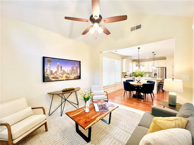 living room featuring vaulted ceiling, ceiling fan, and light wood-type flooring