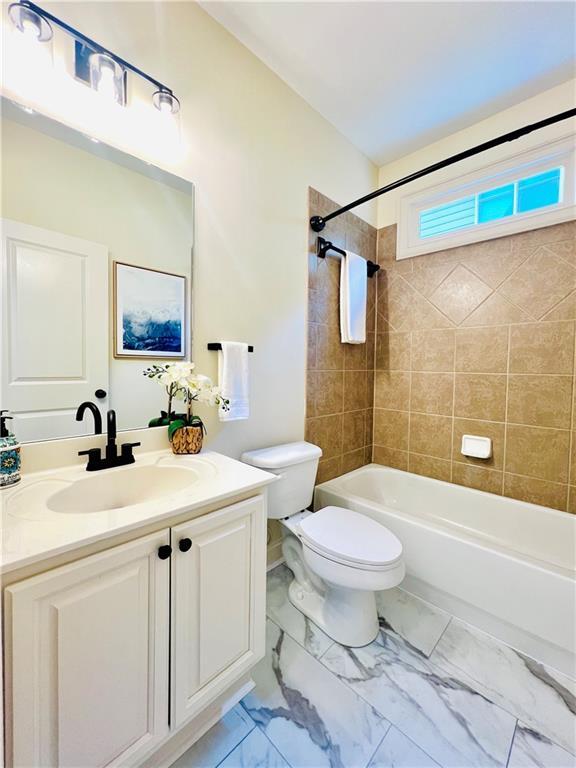 full bathroom with vanity, tiled shower / bath combo, and toilet