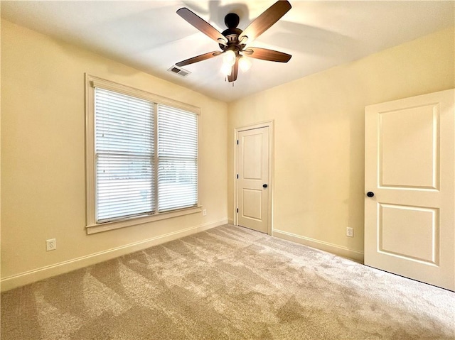 spare room with ceiling fan and light colored carpet