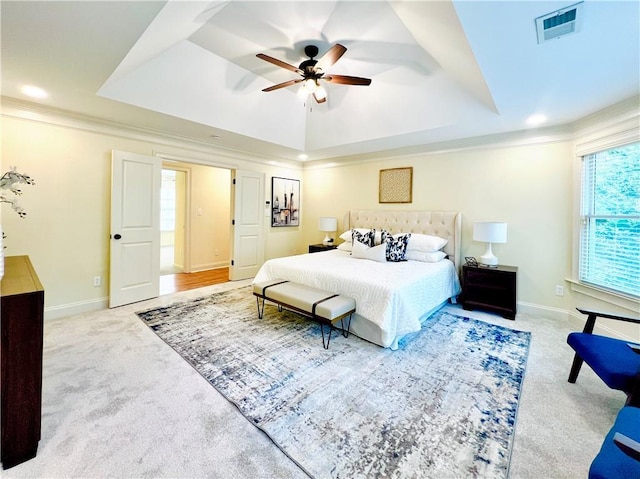 bedroom with crown molding, light carpet, and a tray ceiling