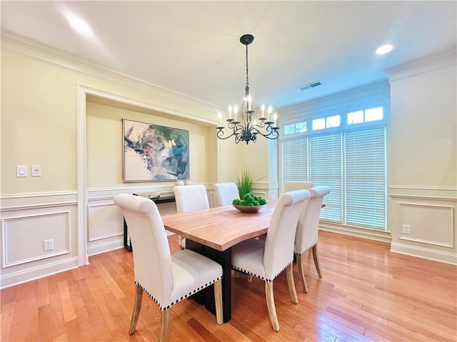 dining space featuring light hardwood / wood-style flooring, ornamental molding, and a chandelier