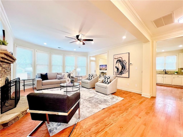 living room with ornamental molding, plenty of natural light, a fireplace, and light hardwood / wood-style floors