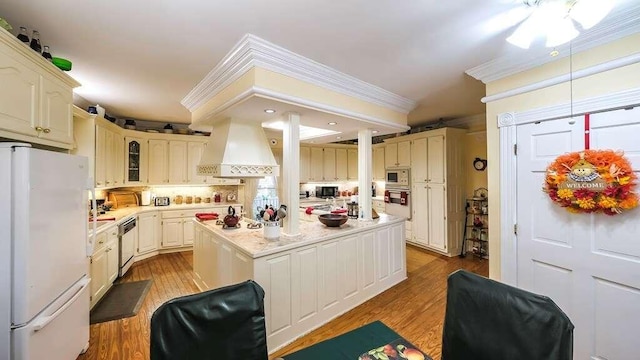 kitchen featuring custom exhaust hood, a center island, light wood-type flooring, appliances with stainless steel finishes, and tasteful backsplash