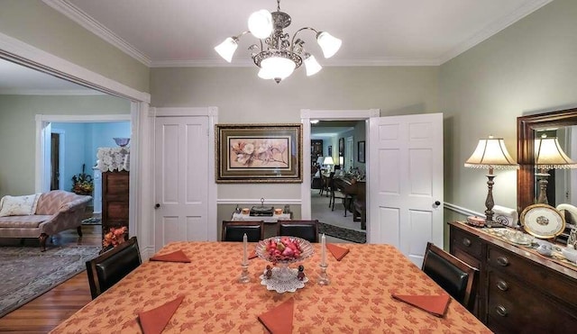 dining room with wood-type flooring, ornamental molding, and an inviting chandelier