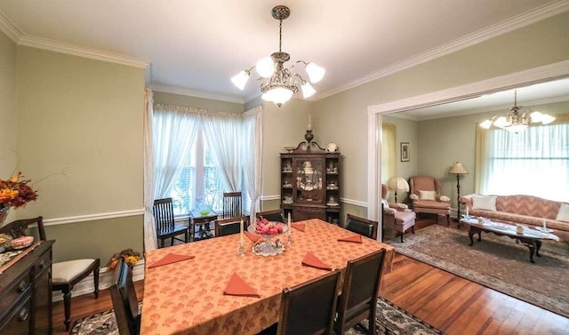 dining space with hardwood / wood-style flooring, crown molding, and an inviting chandelier
