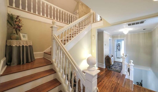 staircase with hardwood / wood-style flooring and crown molding