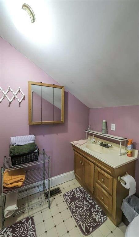 bathroom featuring vanity, toilet, and vaulted ceiling