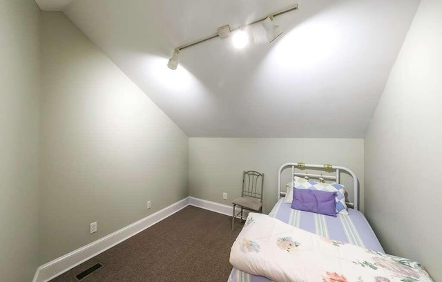 bedroom featuring vaulted ceiling, dark carpet, and track lighting