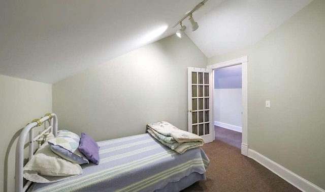 carpeted bedroom with rail lighting and vaulted ceiling