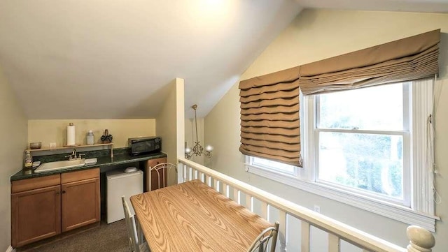 kitchen featuring sink, fridge, decorative light fixtures, vaulted ceiling, and dark carpet