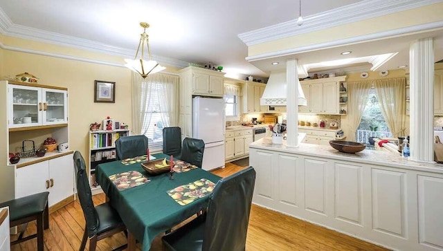 dining room with light hardwood / wood-style floors, plenty of natural light, and crown molding