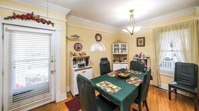 dining room with hardwood / wood-style flooring, crown molding, and a wealth of natural light