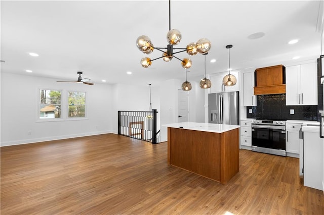 kitchen featuring stainless steel appliances, white cabinets, open floor plan, a center island, and pendant lighting