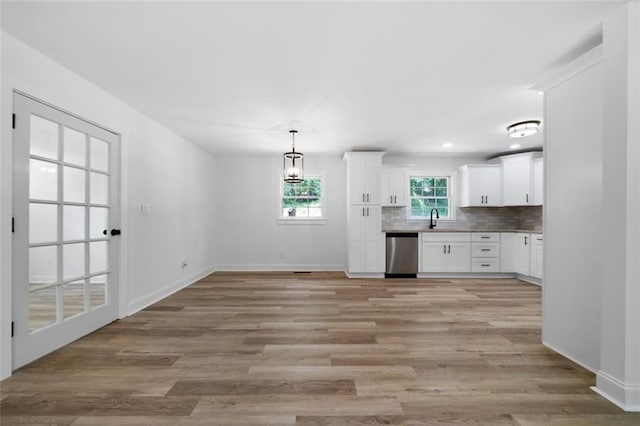 kitchen with white cabinets, dishwasher, light hardwood / wood-style floors, tasteful backsplash, and hanging light fixtures