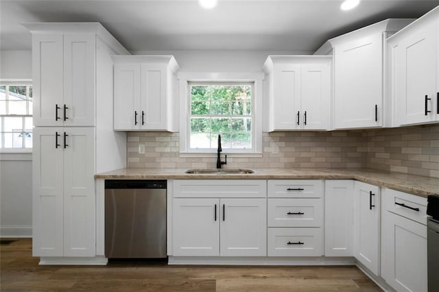 kitchen featuring dishwasher, light stone countertops, sink, white cabinets, and tasteful backsplash